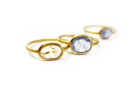 Three slim gold rings with sapphires lined up on a white surface
